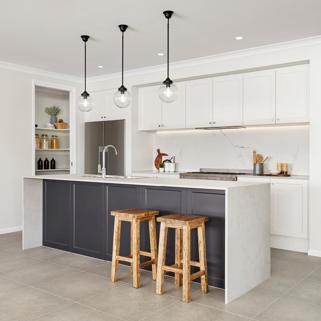 Modern kitchen with a charcoal island, white marble waterfall countertop, and rustic wooden stools.