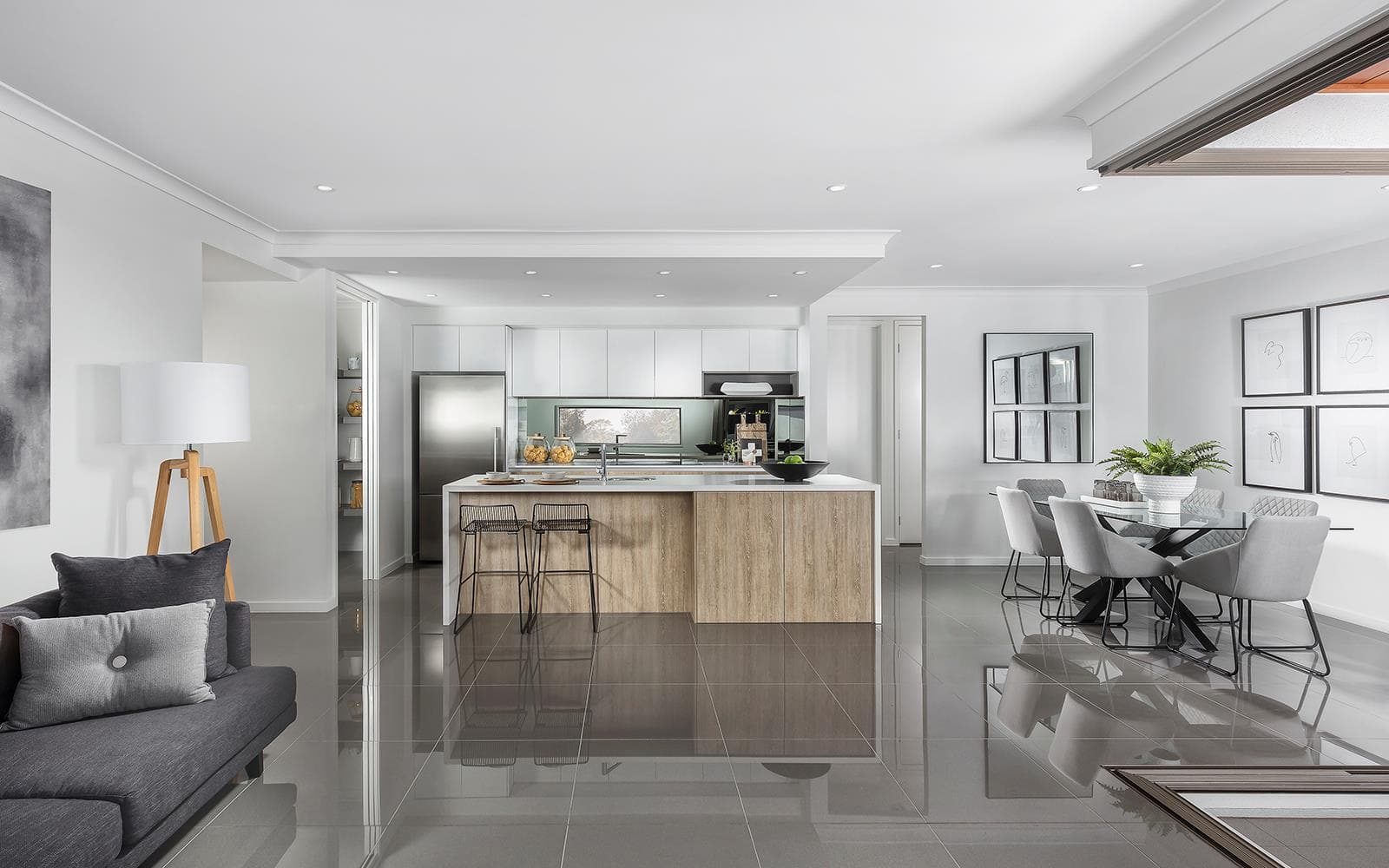 Modern open-plan living space with wooden kitchen island, dining area, and polished tile floors.